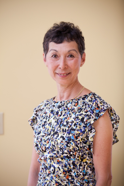 A woman in a flowered dress smiles. 